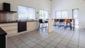 Eine moderne Küche mit einer zentralen Kochinsel, Barhocker und großen Fenstern.
