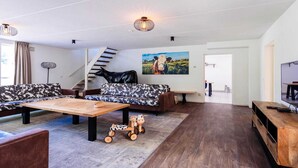 Ein modernes Wohnzimmer mit einer Sofagarnitur, einem Couchtisch, einem TV-Schrank und einer Treppe, die in eine andere Ebene führt.