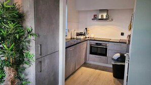 A modern kitchen with a built-in oven, stainless steel appliances, and a wooden floor.