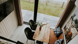 A dining area with a wooden table, black chairs, and a vase with greenery. - Charming Tiny House Getaway with Terrace. (Balkbrug)
