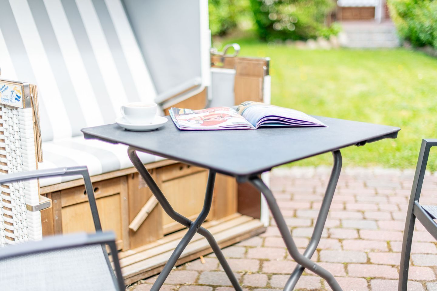 Uma área externa com mesa, cadeiras e uma revista.