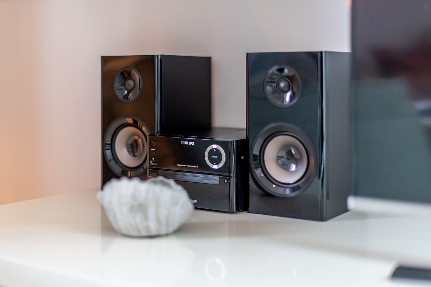 Eine schwarze Audioanlage mit zwei großen Lautsprechern und einer Steuereinheit auf einer weißen Oberfläche.