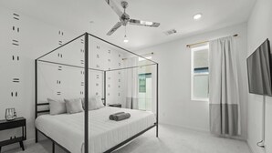 A modern bedroom with a four-poster bed, a ceiling fan, and a TV mounted on the wall. - Modern Townhome Dallas Bishop Arts (Dallas)