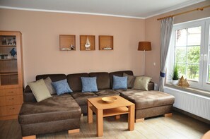 A living room with a brown sectional sofa, a wooden coffee table, and a cabinet with glass doors.