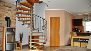 Un salon moderne doté d’un escalier en colimaçon, d’une cheminée, d’un coin repas et d’une cuisine.