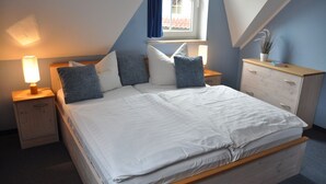 Une chambre à coucher avec un grand lit, deux tables de chevet, une commode, une coiffeuse et une fenêtre avec des rideaux.