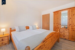 Une chambre à coucher avec un lit en bois, une table de chevet, une armoire et un miroir.