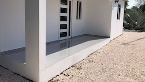 A white building with a covered porch, two windows, and a small entryway. - Peaceful Willemstad Getaway - Entire Apartment for Rent (Willemstad)