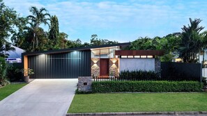 A modern house with a large garage, a stone entrance, and a well-maintained lawn. - Casa Ponta | Port Douglas (PORT DOUGLAS)