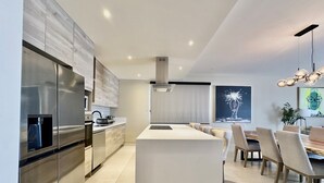 Una cucina moderna con elettrodomestici in acciaio inossidabile, un'isola centrale e un'area pranzo con tavolo e sedie in legno.