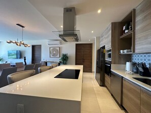 A modern kitchen with a central island, stainless steel appliances, and a dining area with a large table and chairs.