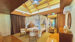 Une chambre à coucher avec un lit à baldaquin, des meubles en bois, une petite table et un ventilateur de plafond.