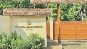 L’entrée du Mandala Beach Resort se distingue par un panneau indicateur, une structure à toit de chaume et un portail en bois.