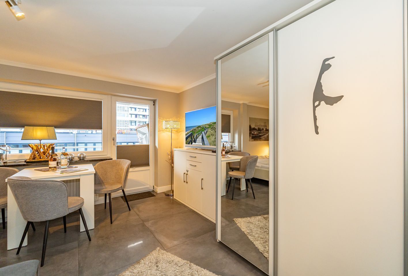 Ein modernes Hotelzimmer mit Essbereich, Fernseher und Blick auf die Stadt.