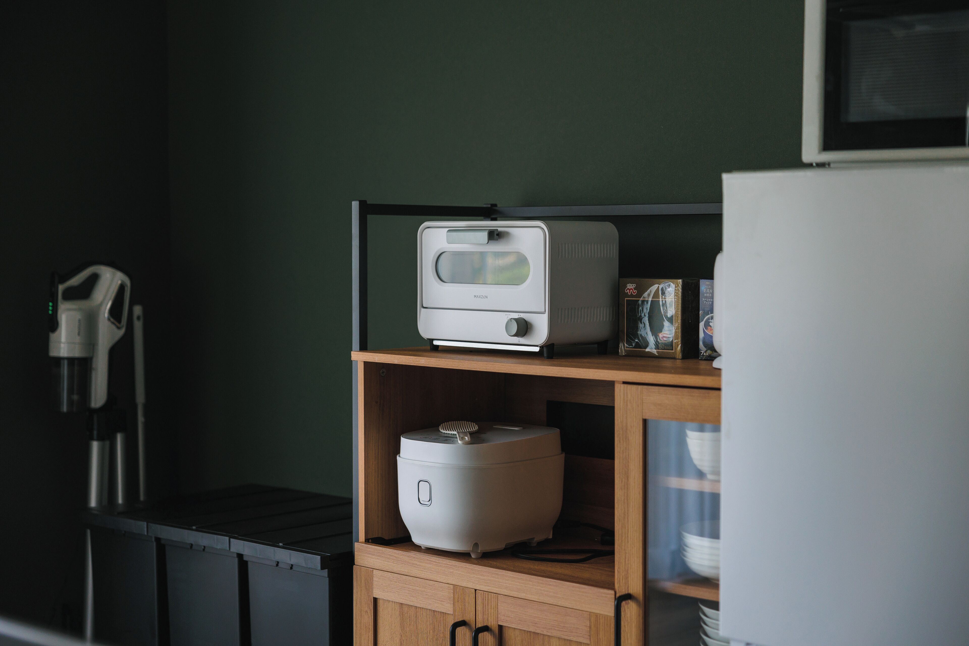 A kitchen with a microwave, a rice cooker, and a coffee maker on a shelf.