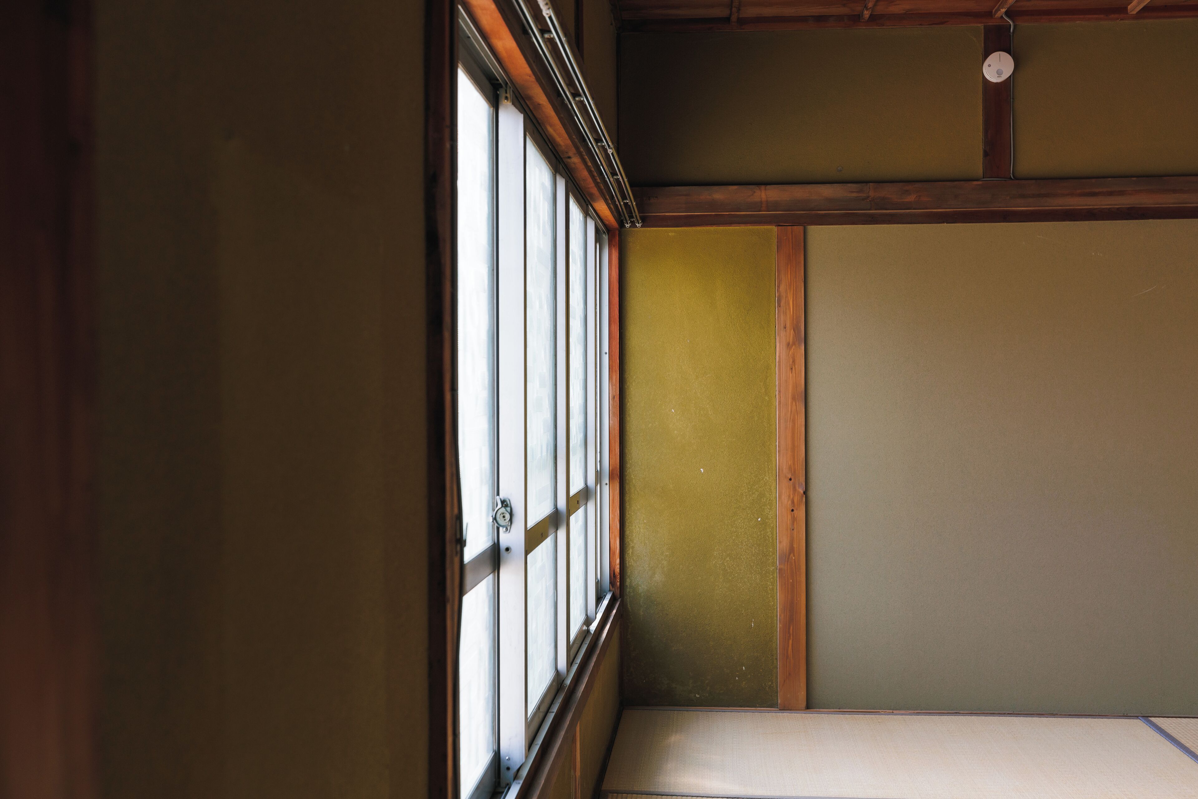 A traditional Japanese room with tatami flooring, shoji screens, and a wooden ceiling.