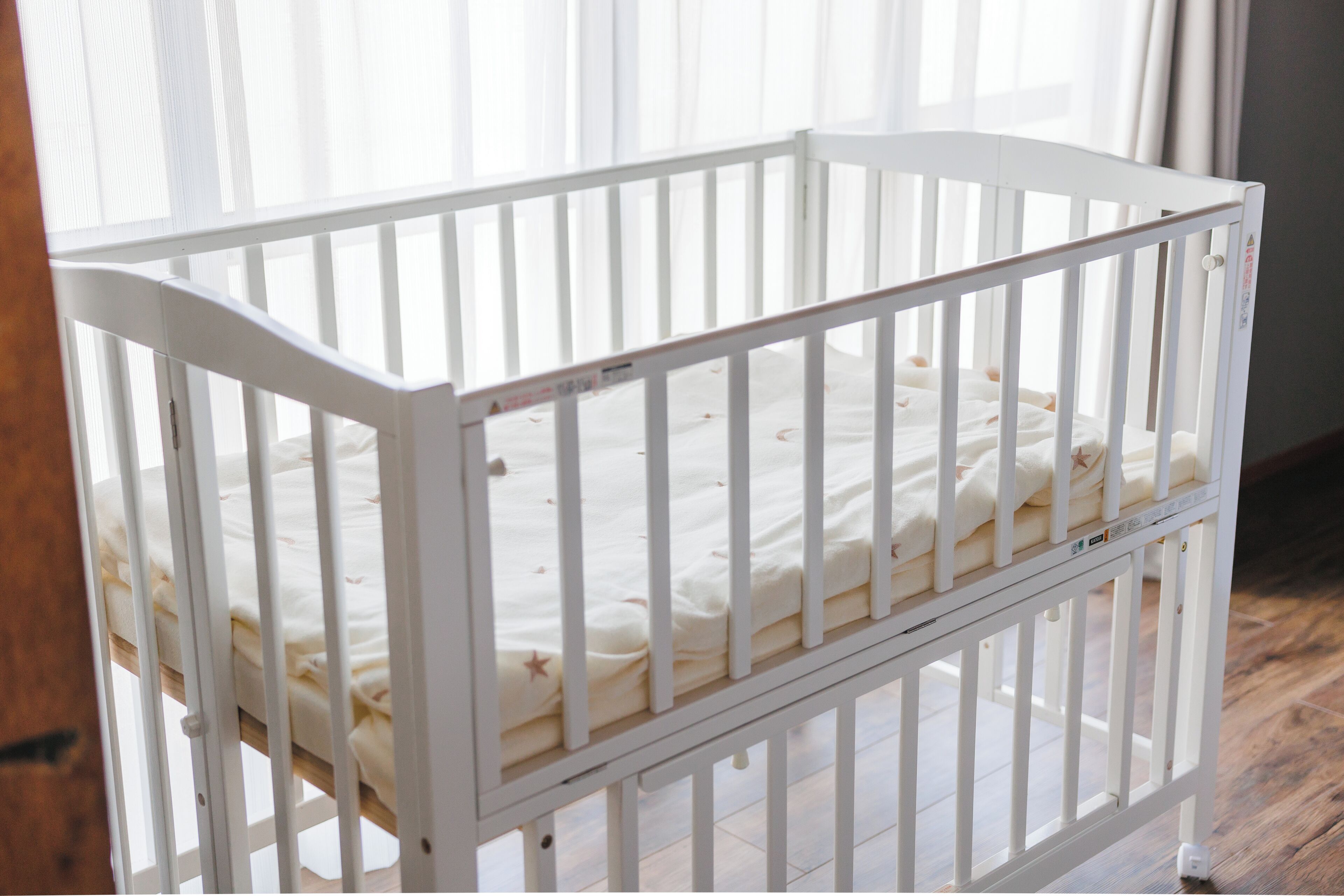 Un berceau blanc avec un matelas blanc et un plancher en bois.