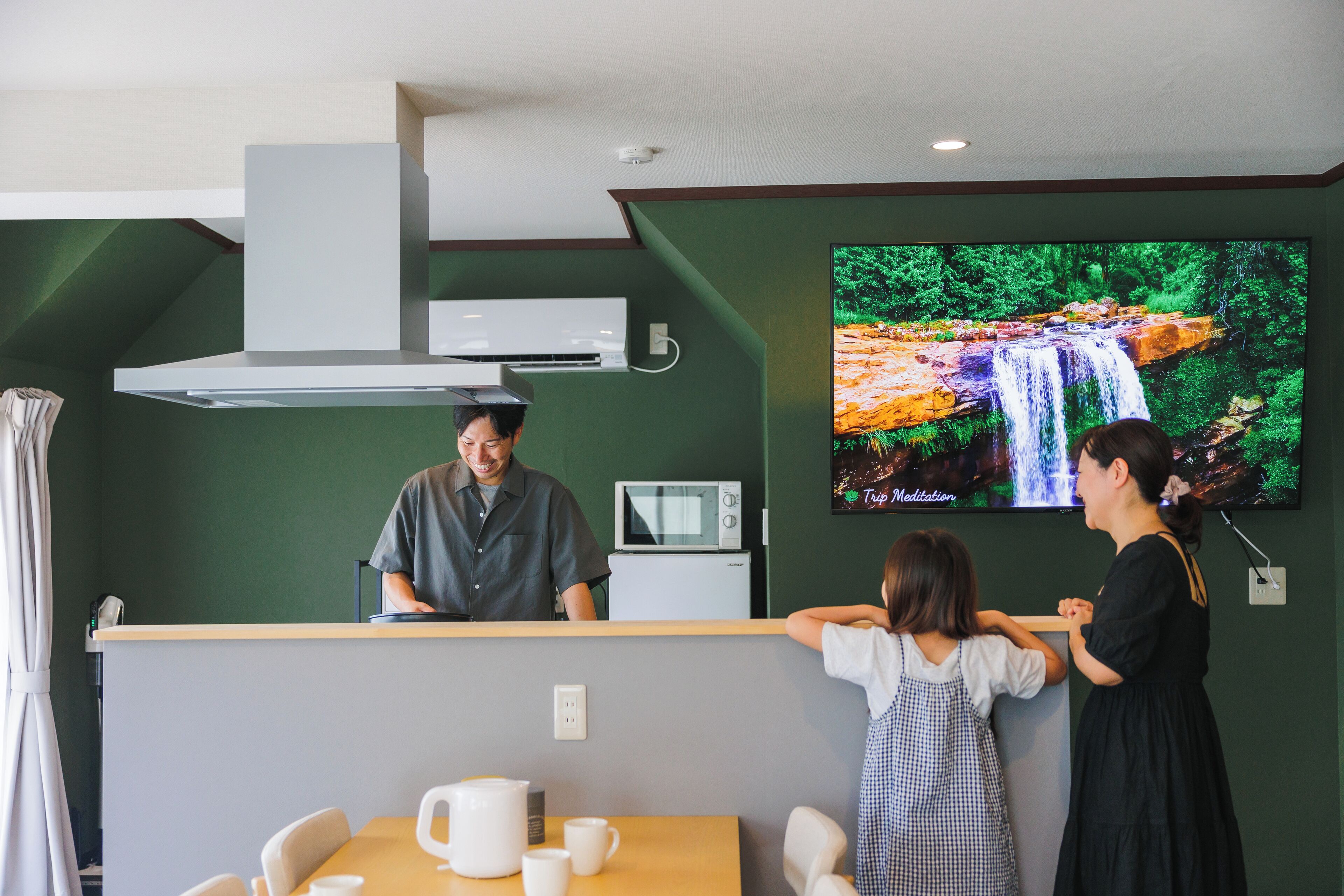 A reception area with a counter, a microwave, and a TV displaying a waterfall scene.