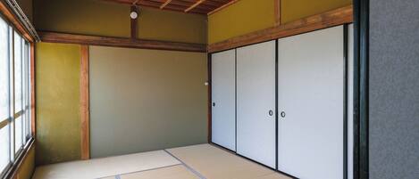A traditional Japanese room with tatami flooring, sliding doors, and a wooden ceiling.