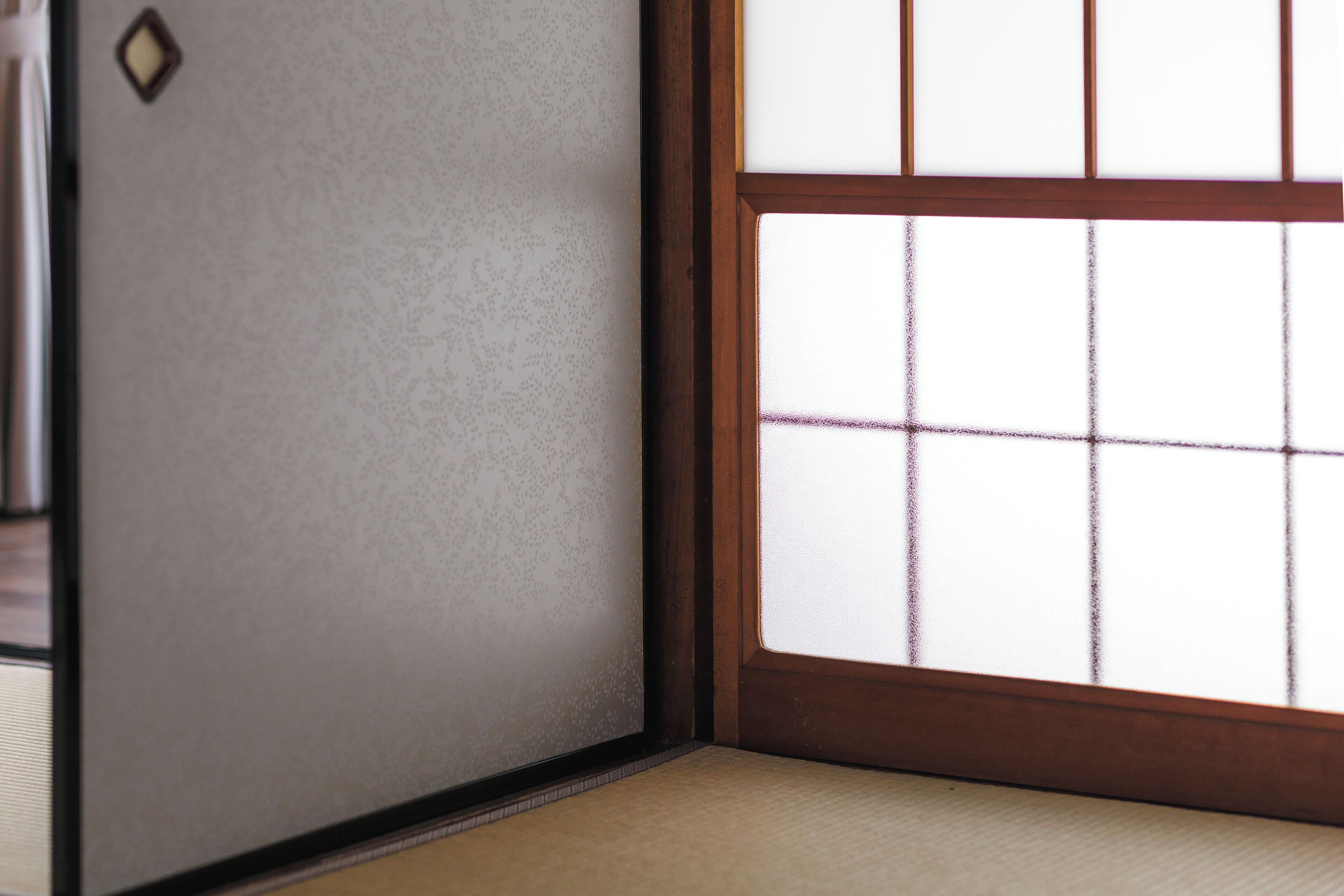A traditional Japanese room with tatami flooring, a shoji screen door, and a wooden frame.