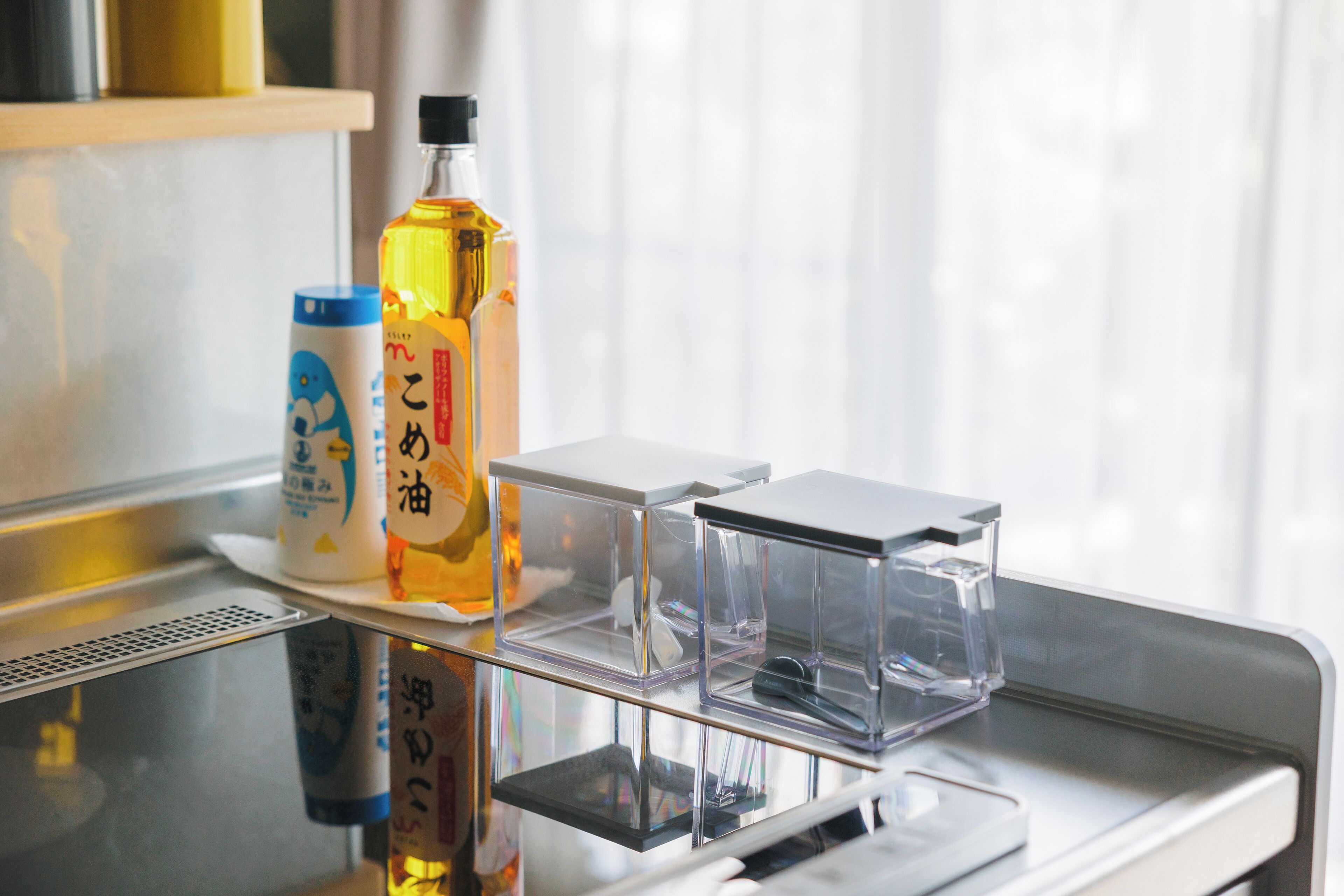 Una encimera de cocina con un microondas, una botella de aceite para cocinar y un recipiente de salsa de soja.