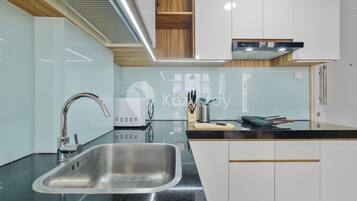 Een moderne keuken met een roestvrijstalen spoelbak, zwarte aanrechtbladen en witte keukenkastjes.
