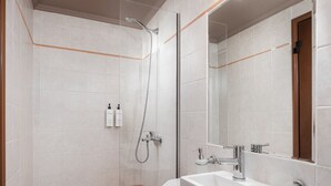 Een moderne badkamer met een douche, wastafel en spiegel.