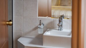 Een badkamer met een wit wastafel, een spiegel en een handdoekdispenser.