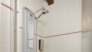 A shower with a handheld showerhead and multiple control knobs.