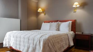 A neatly made bed with white bedding, a wooden headboard, and two wall-mounted lamps.