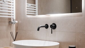 Un baño moderno con un lavamanos ovalado grande, un grifo negro y un espejo encima.