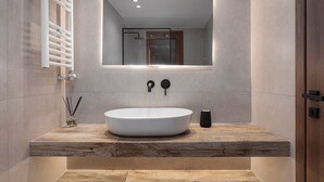 Un baño moderno con un lavamanos ovalado grande, un espejo y un perchero para toallas.