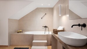 Un baño moderno con una bañera independiente, un lavamanos grande y una ducha.
