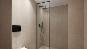Un baño moderno con ducha de vidrio, inodoro y panel de control en la pared.