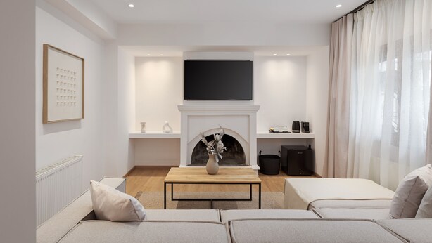 Un salon moderne avec une cheminée, un téléviseur à écran plat fixé au-dessus et un ensemble de canapés.