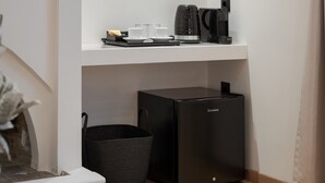 Une petite cuisine équipée d’une machine à café, d’un petit réfrigérateur et d’un panier.