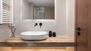 Une salle de bain moderne avec un grand lavabo blanc, un miroir au-dessus et un meuble-lavabo en bois.