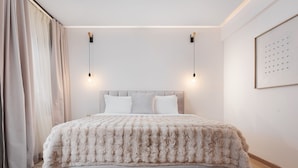 Une chambre à coucher moderne avec un grand lit, deux lampes de chevet et une œuvre d’art encadrée au mur.