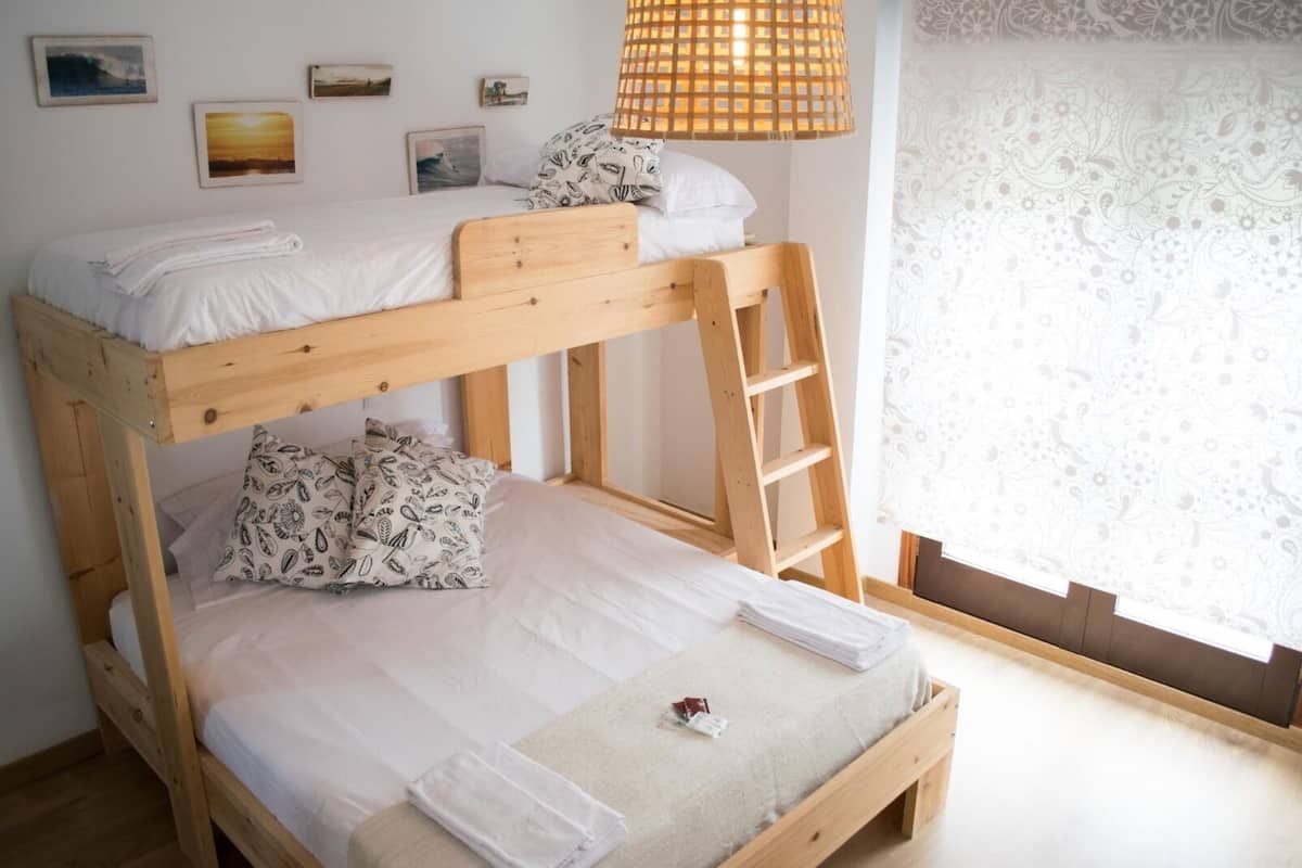 Een stapelbed met een ladder, witte beddengoed en gestreepte kussens.