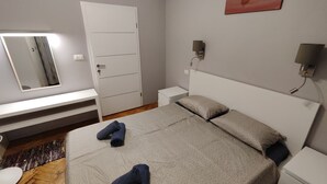 A bedroom with a bed, a bedside table, a nightstand, a mirror, and a wall-mounted lamp. - Pablo accommodation (Rovinj)