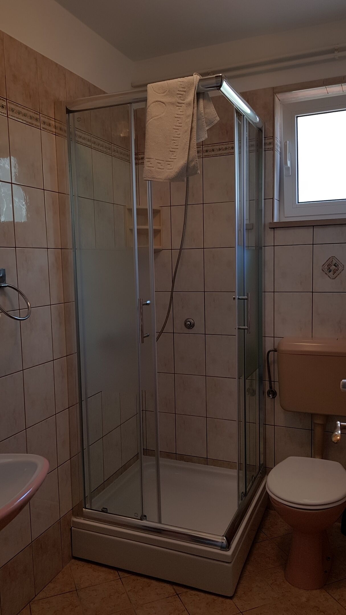 Un baño con cabina de ducha de vidrio, inodoro y lavamanos.