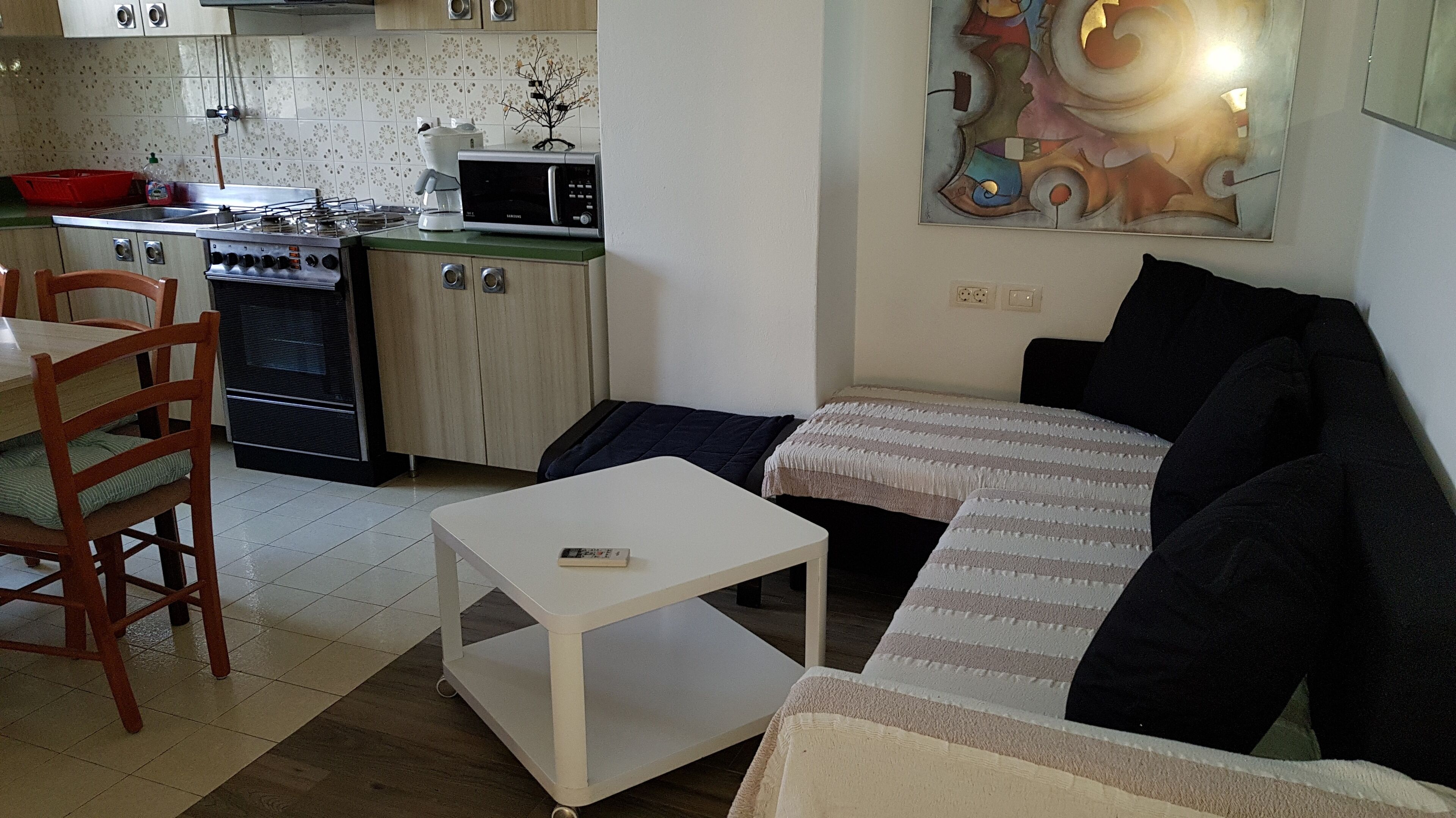 Un espacio habitable compacto con kitchenette, comedor y sofá.