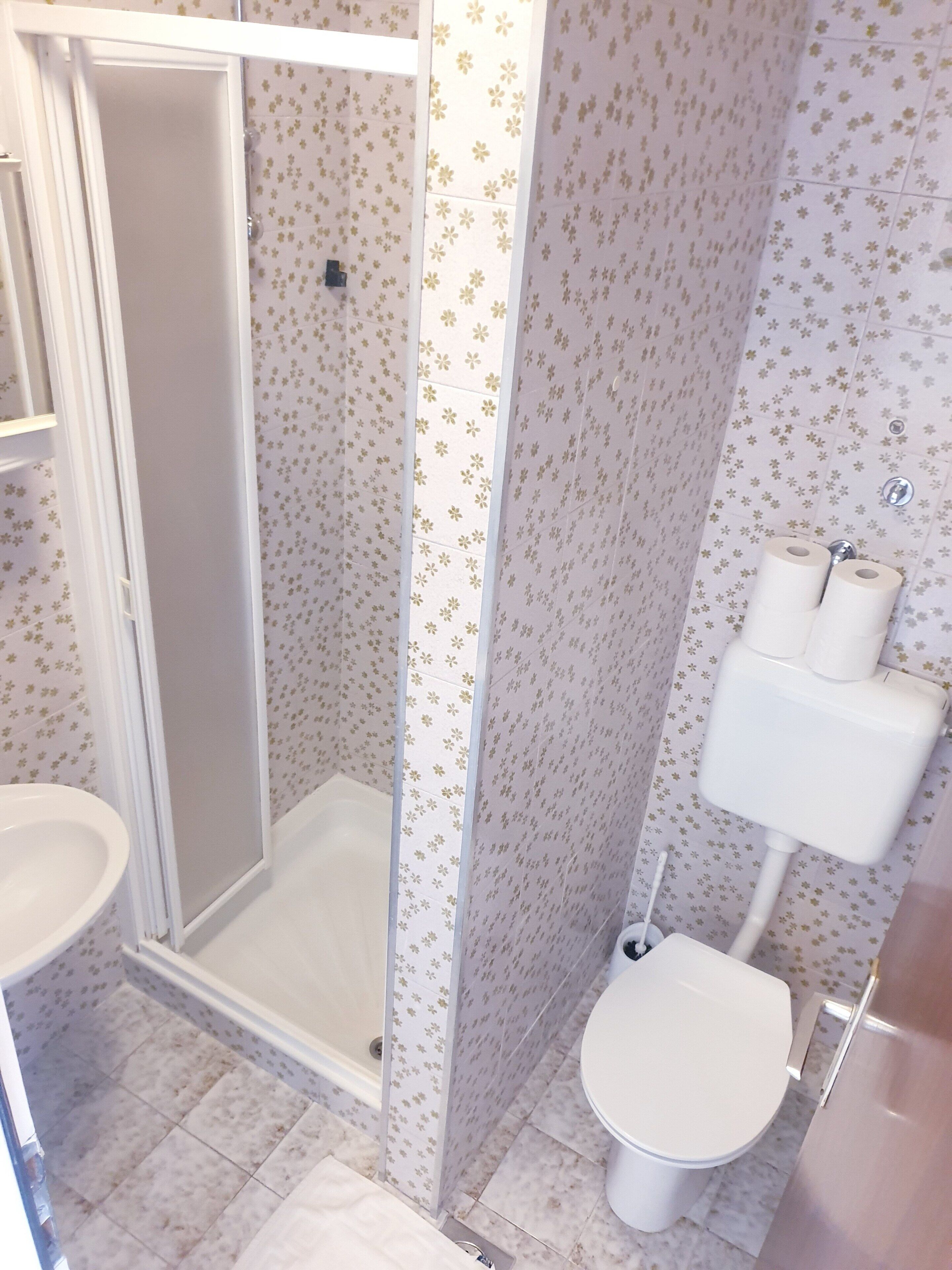 A bathroom with a shower, toilet, and sink.