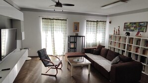 A living room with a sofa, a coffee table, a TV, a bookshelf, and a chair. - Pablo accommodation (Rovinj)