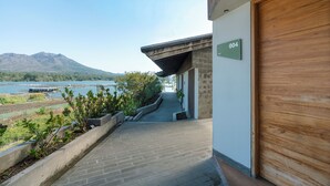 A modern building with a number '004' sign, a wooden door, and a view of a lake and mountains. - Noya Hotel (Kintamani)