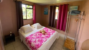 A bedroom with a bed, a window with curtains, a small bedside table, and a wall-mounted drying rack.