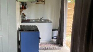 A compact kitchen with a stove, sink, and a small refrigerator.