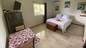 A bedroom with a bed, a desk with a computer, a window, and a ceiling fan.