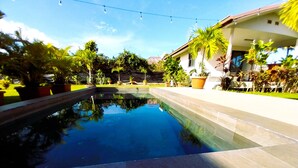A swimming pool with a clear view of the surrounding greenery and a building in the background.