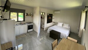 A compact, modern room with a kitchenette, a bed, and a dining area.